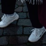 Customize Shoes - a person standing on a cobblestone walkway wearing white sneakers