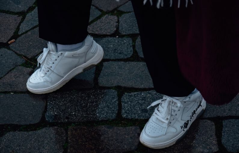 Customize Shoes - a person standing on a cobblestone walkway wearing white sneakers