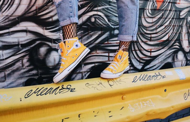 Shoes Affect Posture - person standing on yellow guard rail