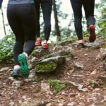 Colorful Shoes - person in black leggings and green sneakers standing on brown rock