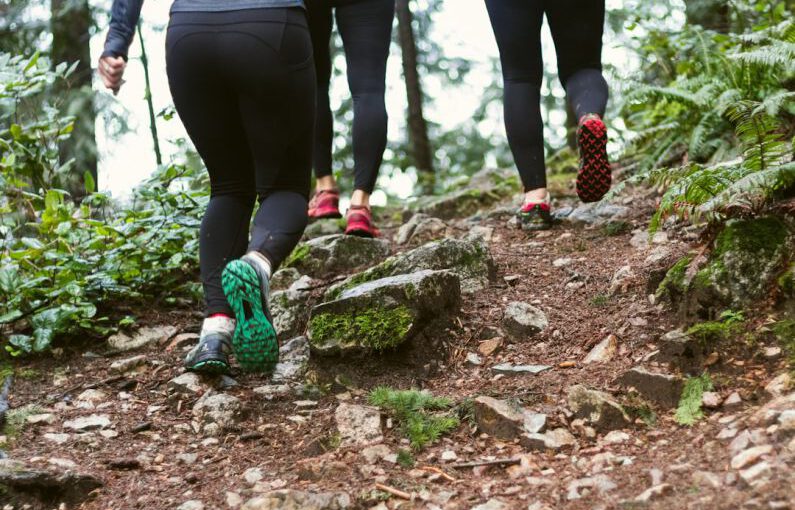 Colorful Shoes - person in black leggings and green sneakers standing on brown rock