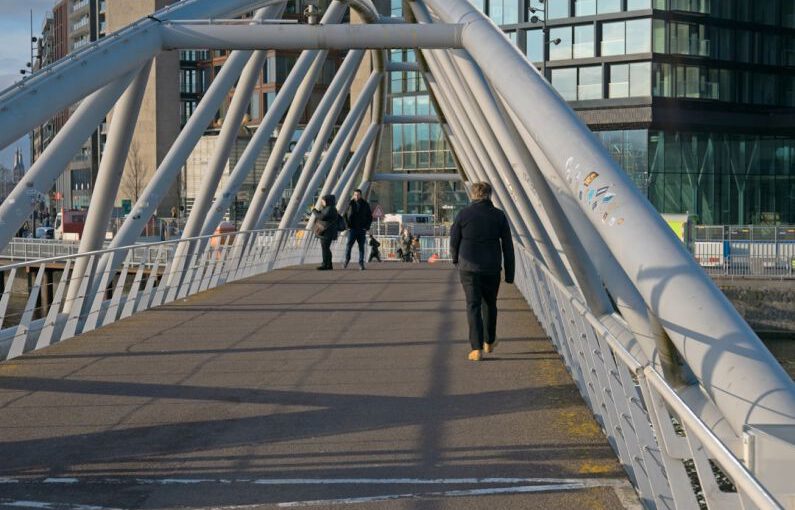 Foot Arch - a man walking across a bridge over a river