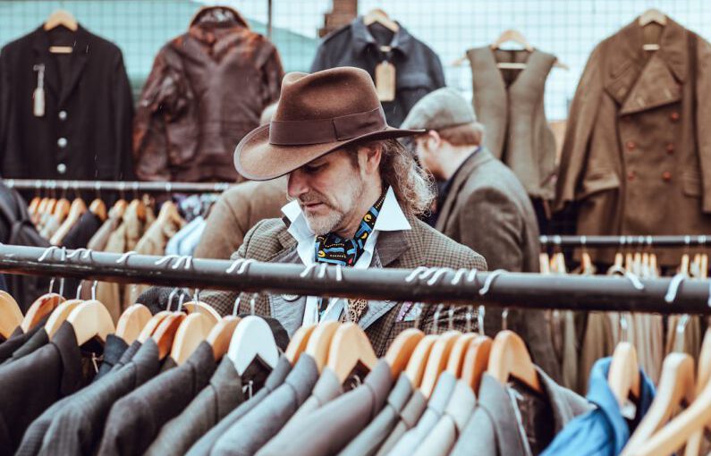 Online Shoes Shopping - man in brown cowboy hat in front of hanged suit jackets