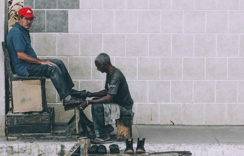 Shoe Polishing - man sitting on stool cleaning shoes at the alley