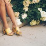 Shoe Embroidery - woman sitting on brown stair beside yellow and white flowers
