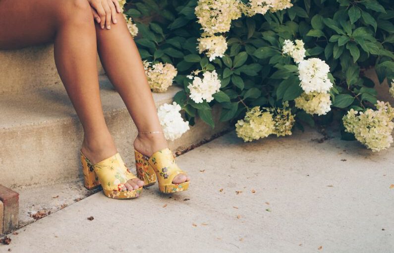 Shoe Embroidery - woman sitting on brown stair beside yellow and white flowers