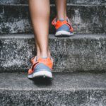 Replace Running - person wearing orange and gray Nike shoes walking on gray concrete stairs