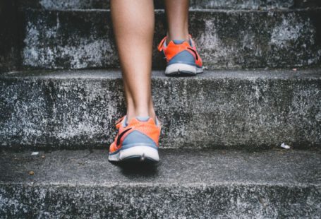 Replace Running - person wearing orange and gray Nike shoes walking on gray concrete stairs