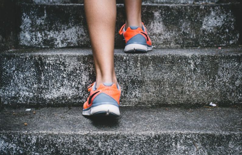 Replace Running - person wearing orange and gray Nike shoes walking on gray concrete stairs